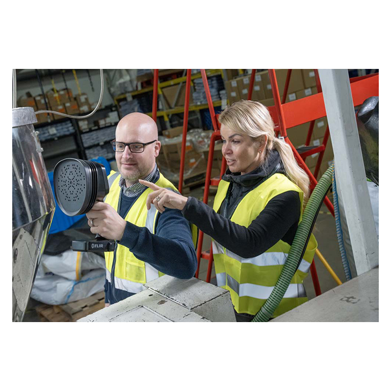 A man and a woman are using the FLIR Si-LD Acoustic Camera to inspect equipment.